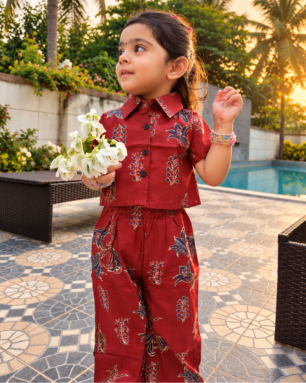 A young girl is standing near a pool wearing a rust colored pure cotton co-ord set from Aruvo