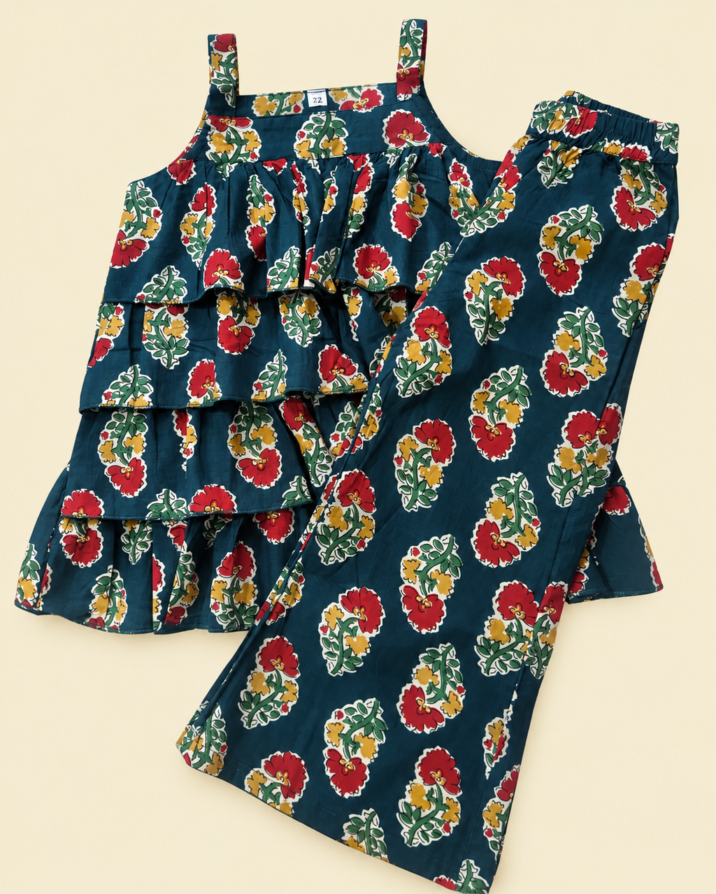 A two-piece girls' outfit set featuring a sleeveless ruffled top and matching wide-leg pants, both in a dark teal blue floral print with red, yellow, and green flowers.