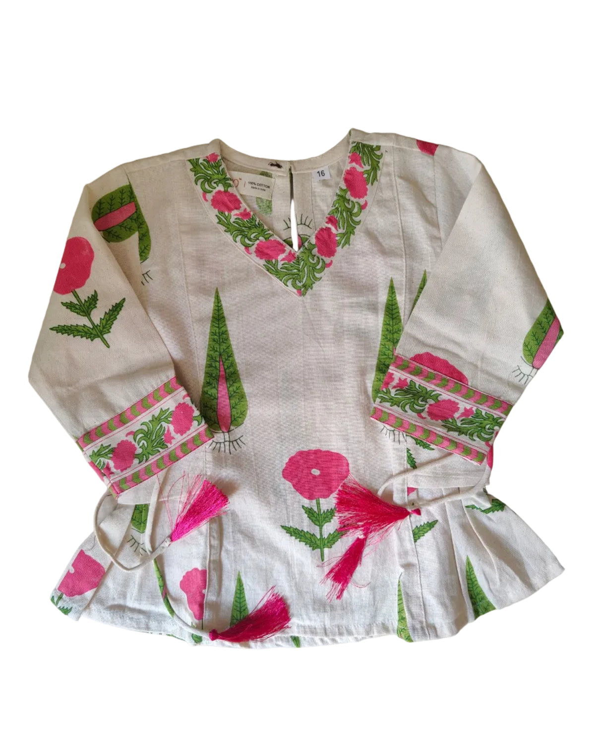 A white sleeveless top with pink floral prints, green leaves, and pink tassels, laid flat on a light beige tiled floor.